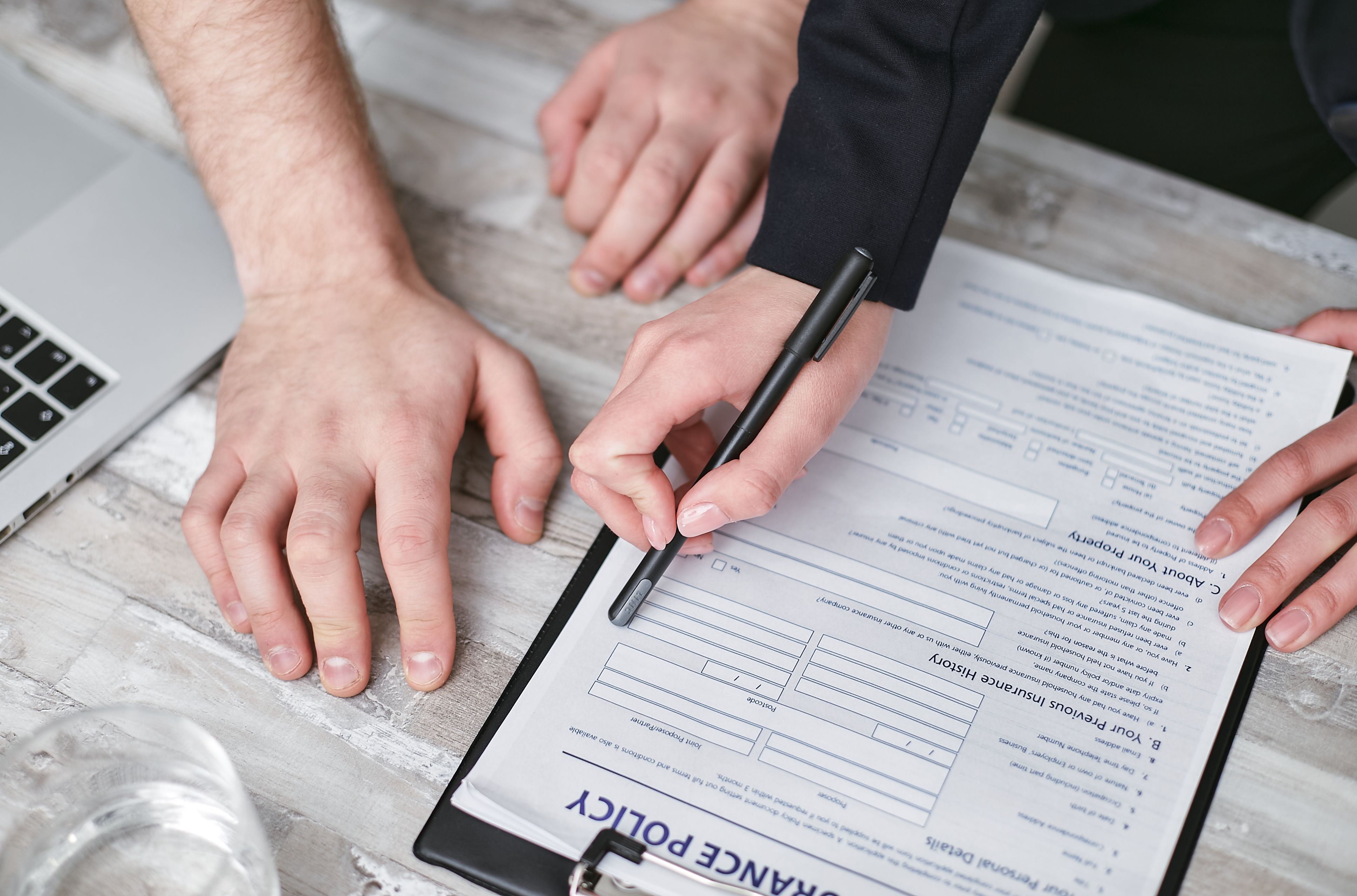 A person at a desk filling out a life insurance application with a laptop and coffee nearby - life insurance options