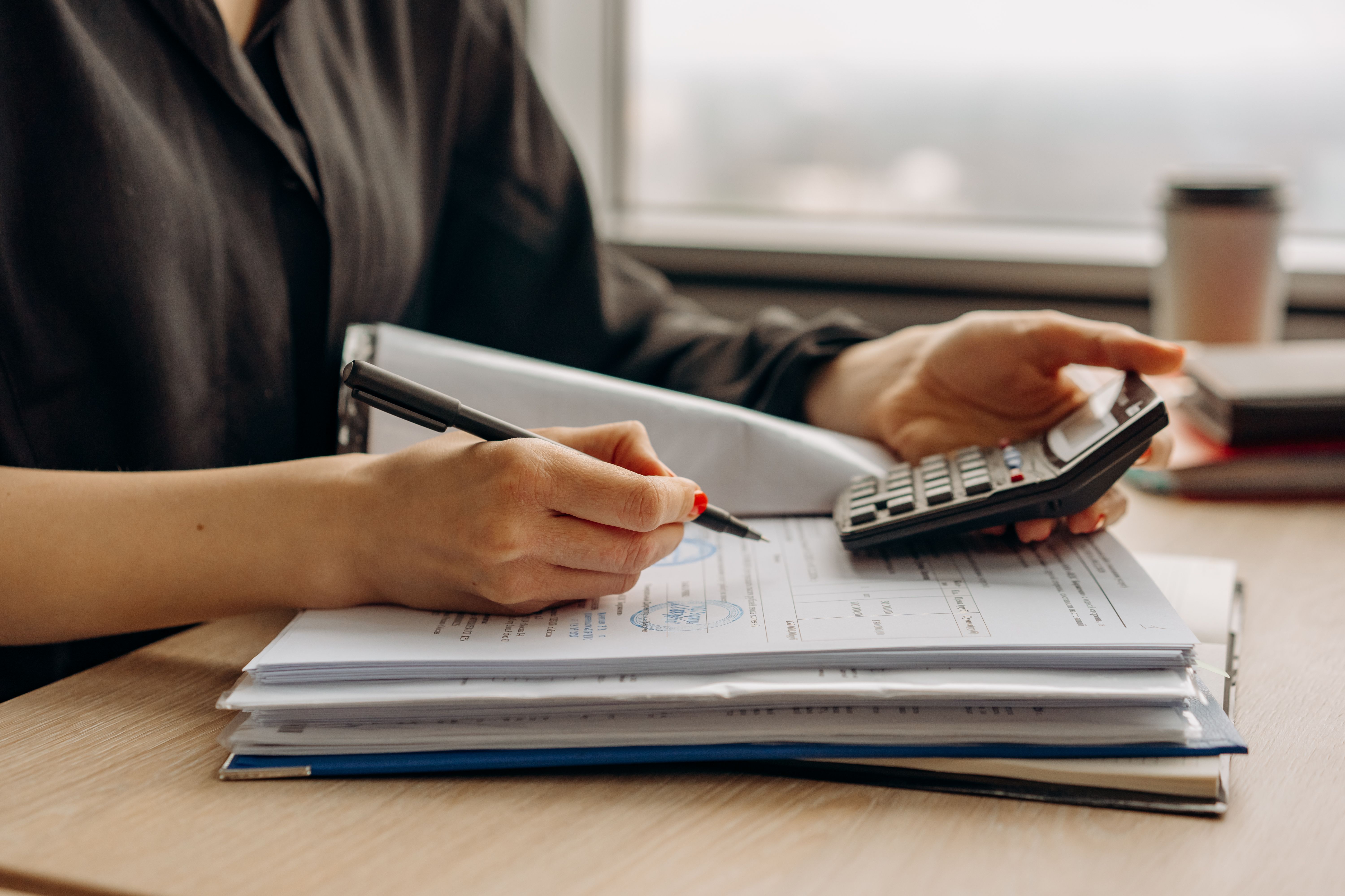 Small business owner using a calculator to determine insurance costs - affordable business insurance Small business owner using a calculator to determine insurance costs - affordable business insurance
